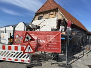 Håndværkere renoverer murstenshus under klart blå himmel